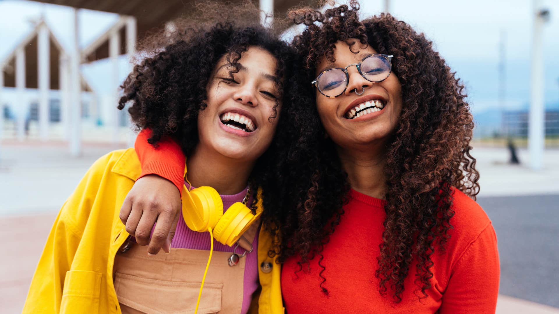 Two teenage girls smiling and hugging each other.