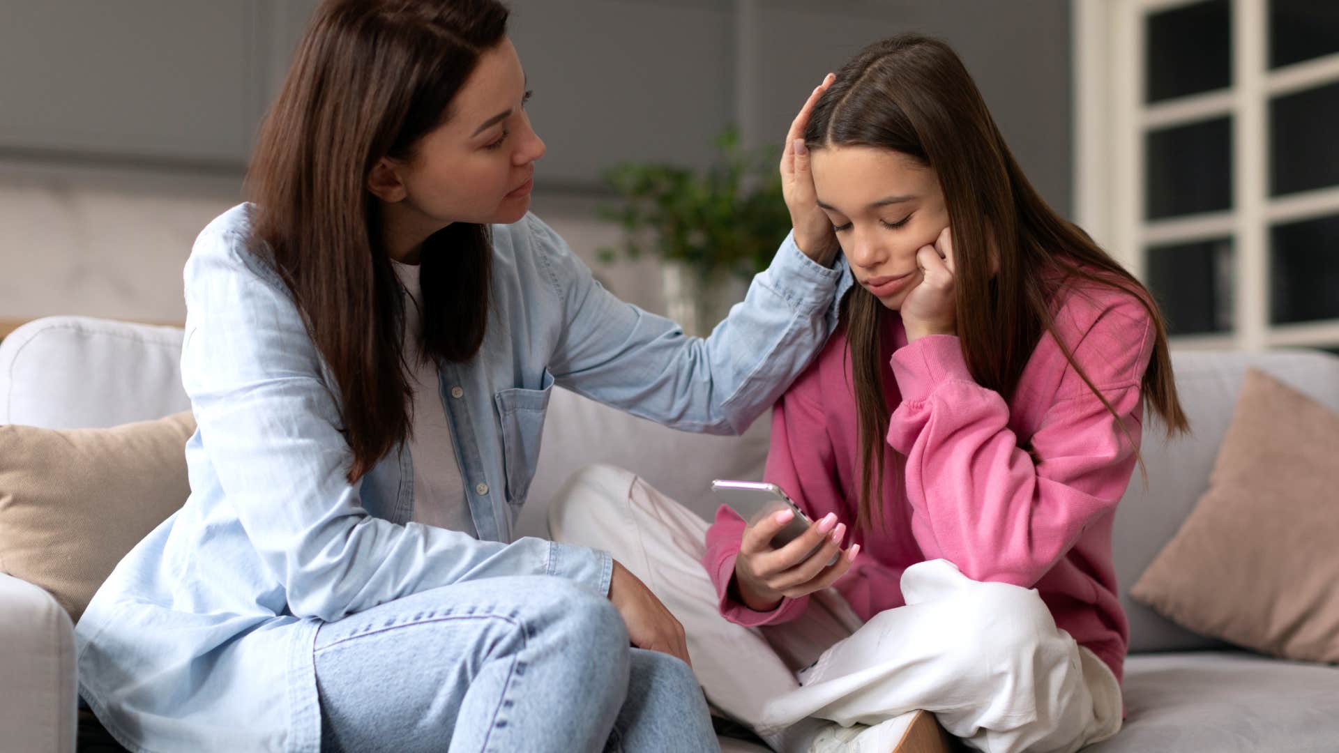 Teenage girl looking sad while being comforted by her mom.