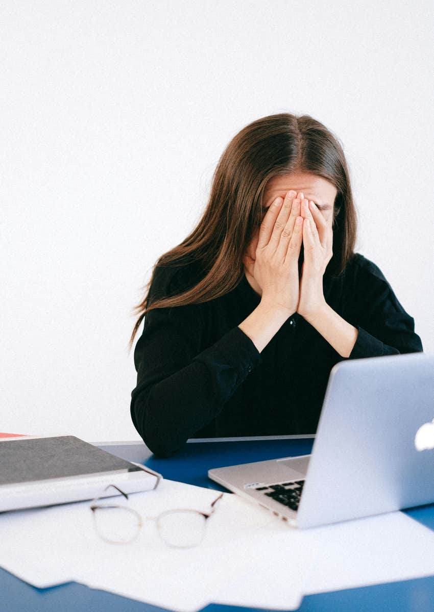 sad woman crying at desk with laptop and papers