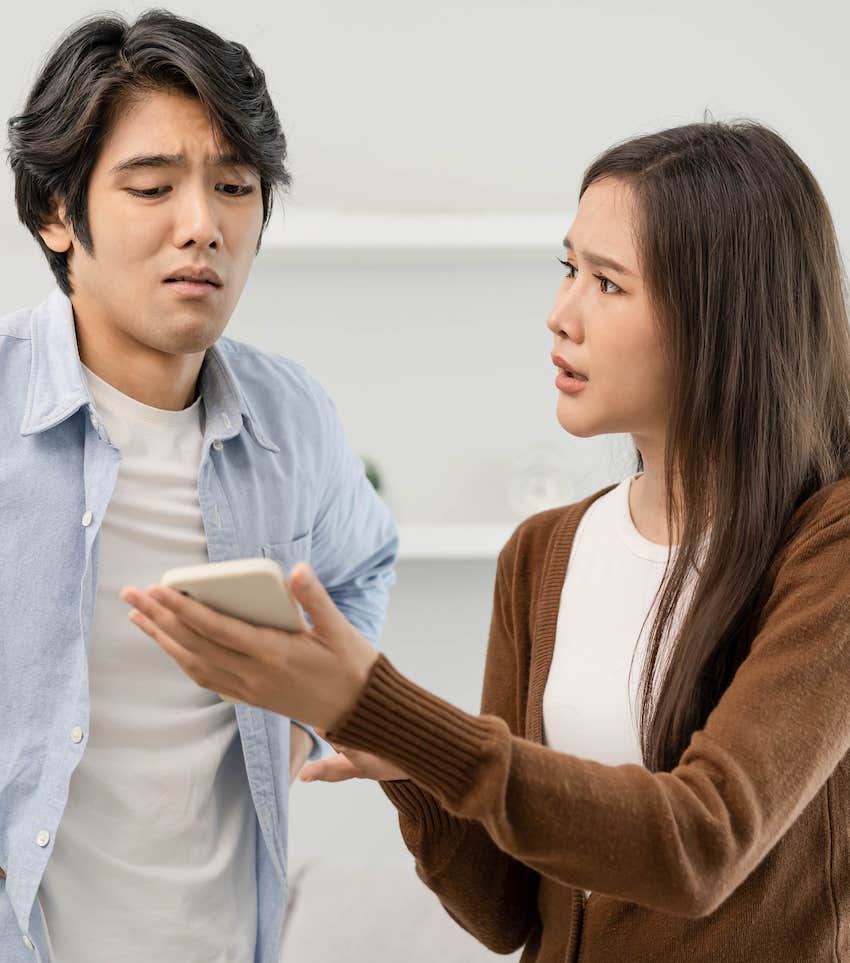 Thoughtful woman shows mobile device to critical man