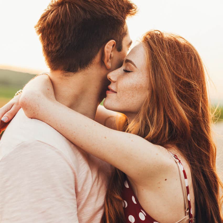 Close-up portrait of a caucasian young loving couple embracing while standing on a roadside.