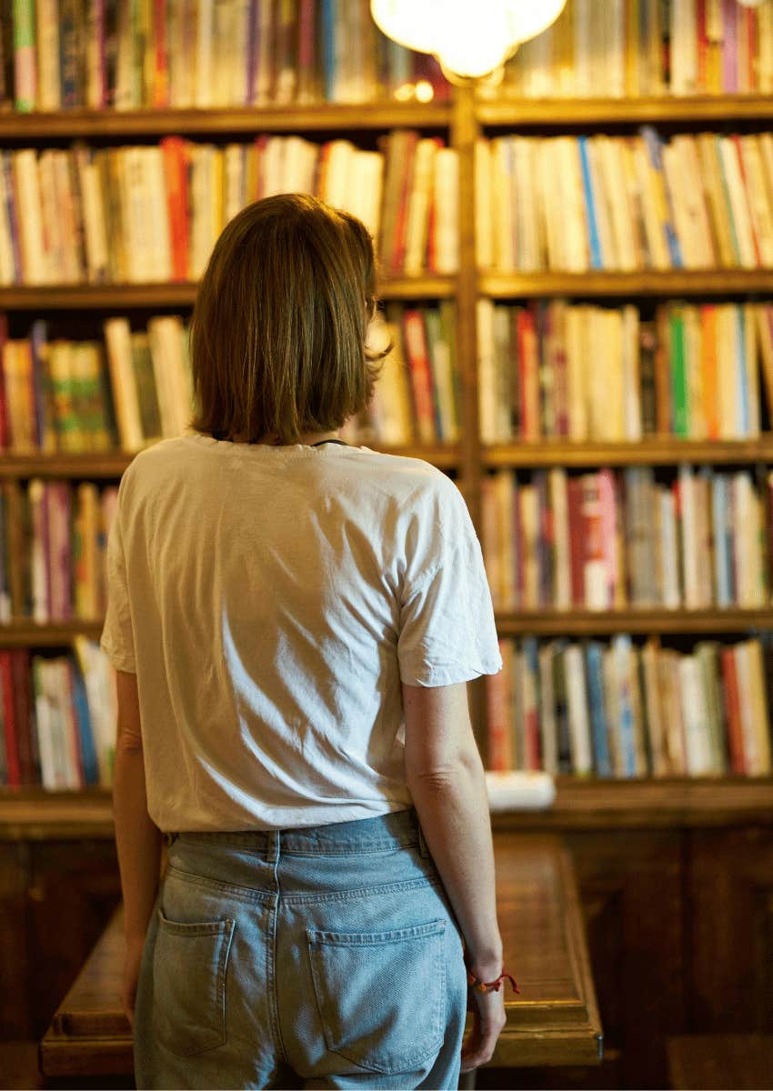 short-haired woman staring at a bookshelf