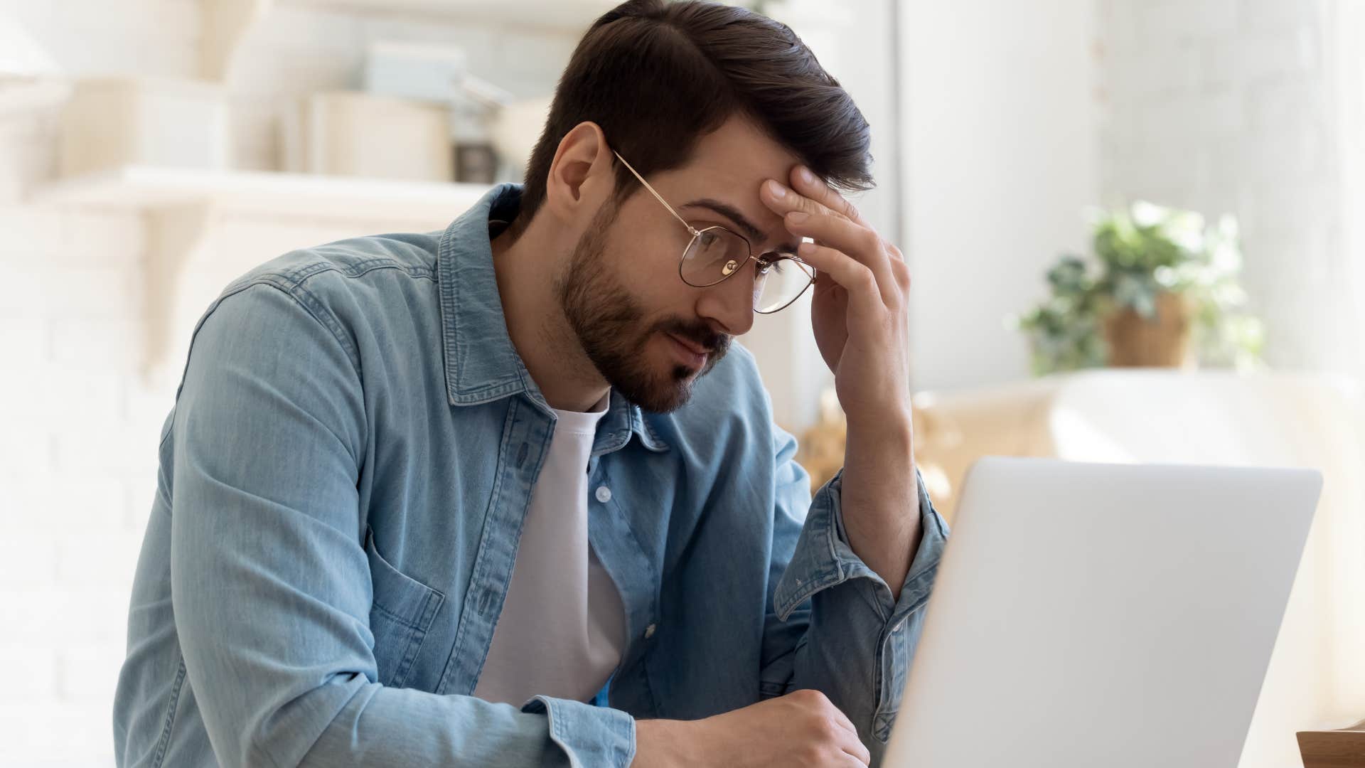 Man looking annoyed at his laptop. 