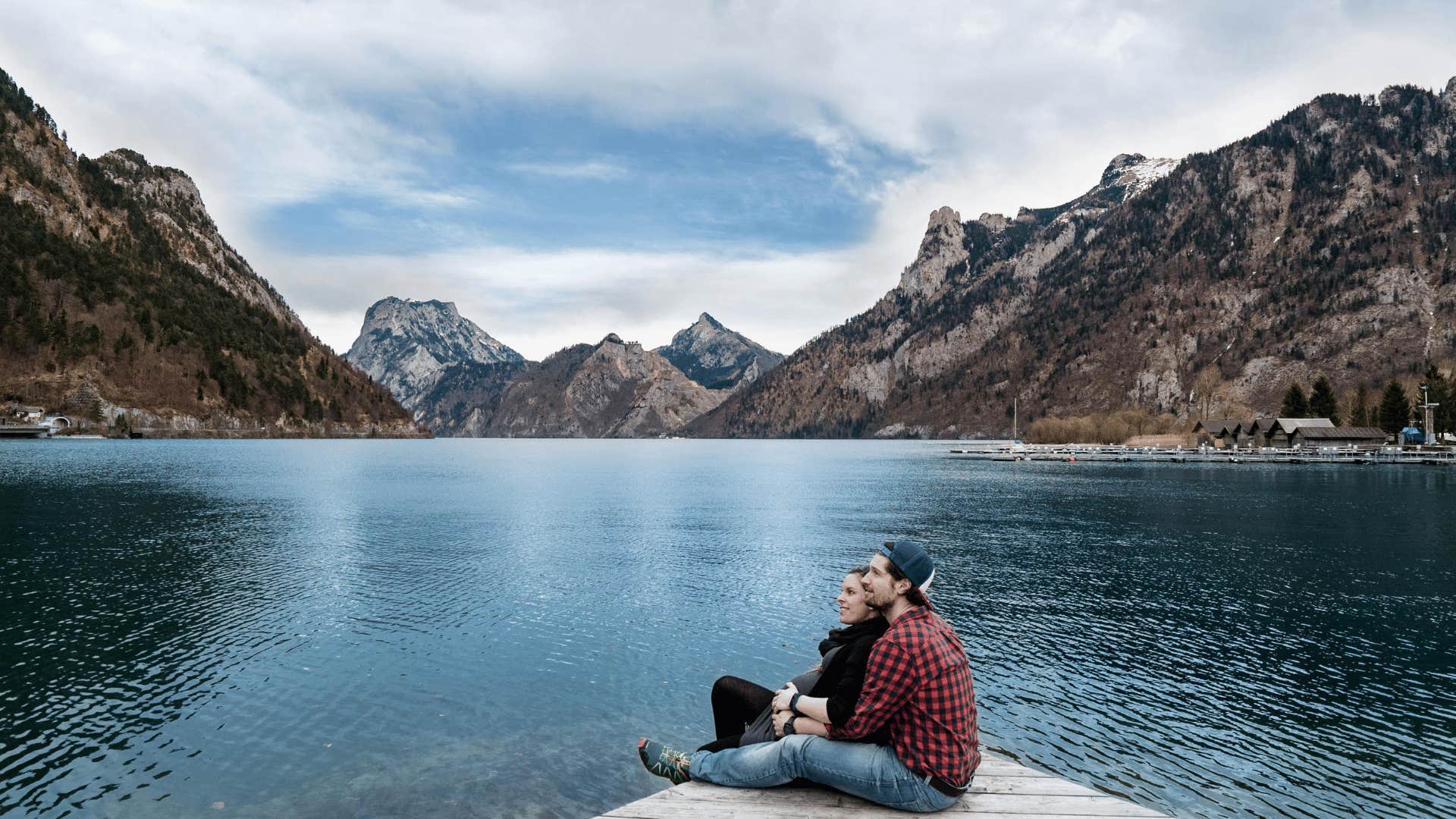 couple sitting together next to mountains and lake