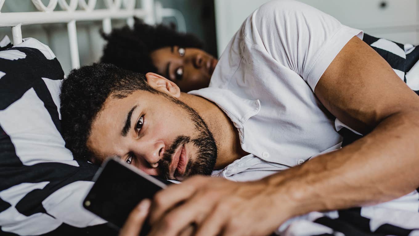 Man texting another woman while partner is in bed with him.