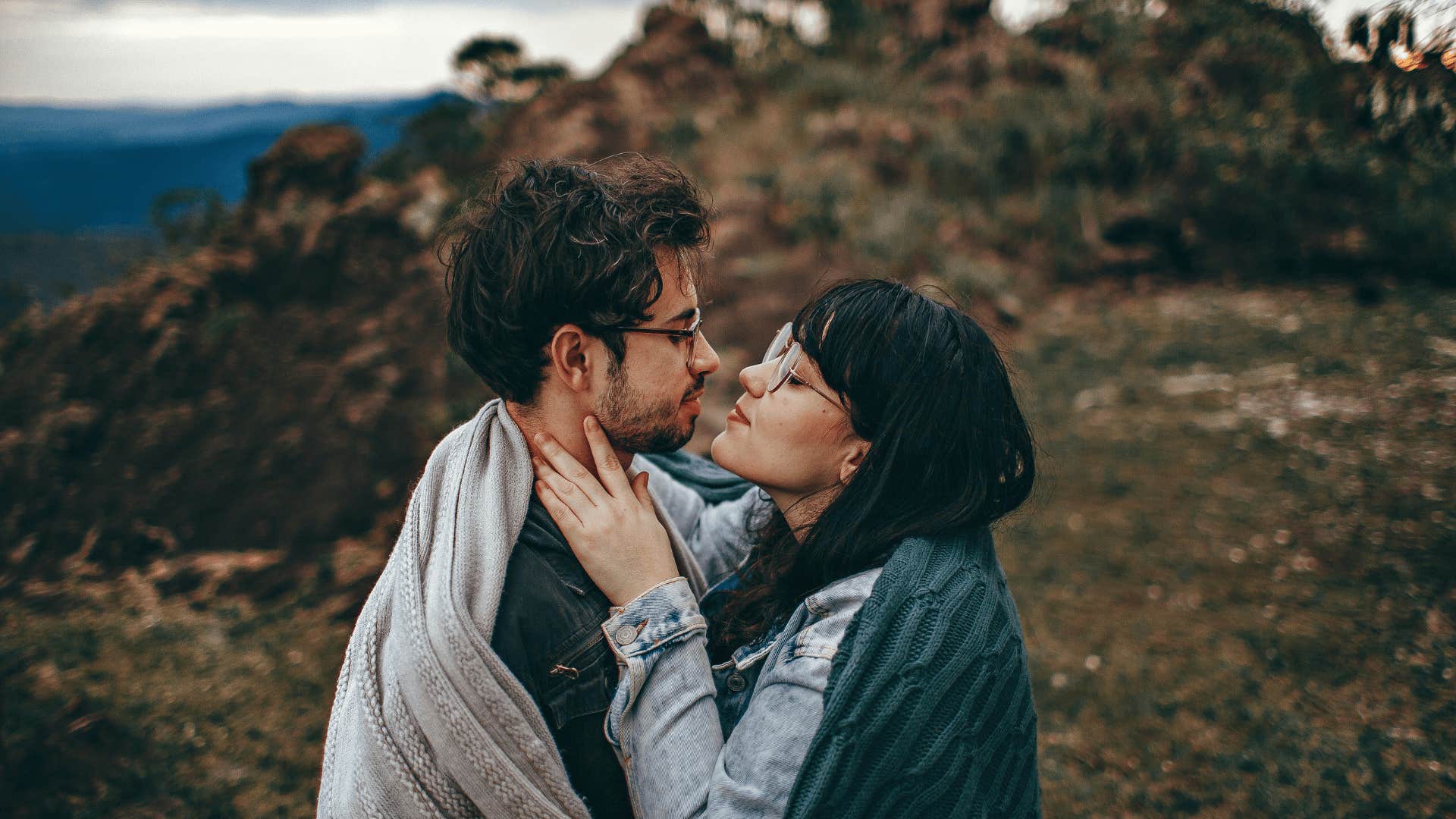 couple embracing wrapped around a blanket