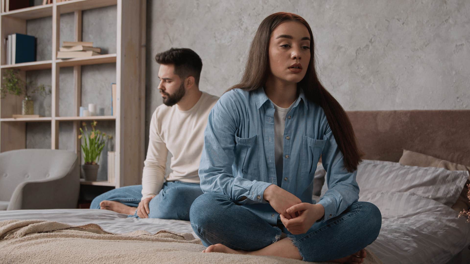 sad woman sitting on bed with husband 