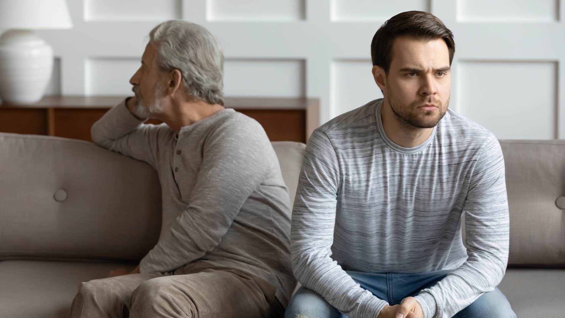 Man turned away from his dad looking annoyed.