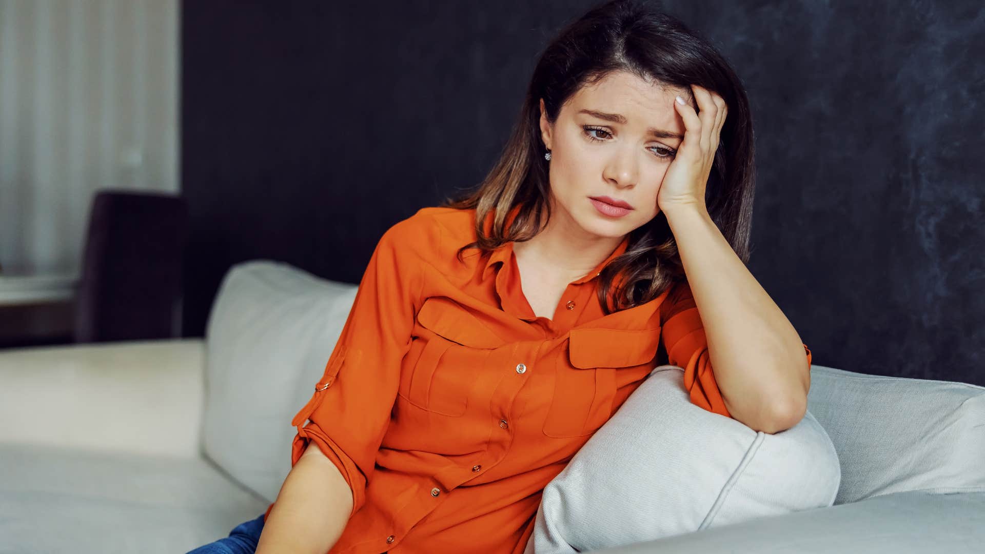 Sad woman sitting on a couch.