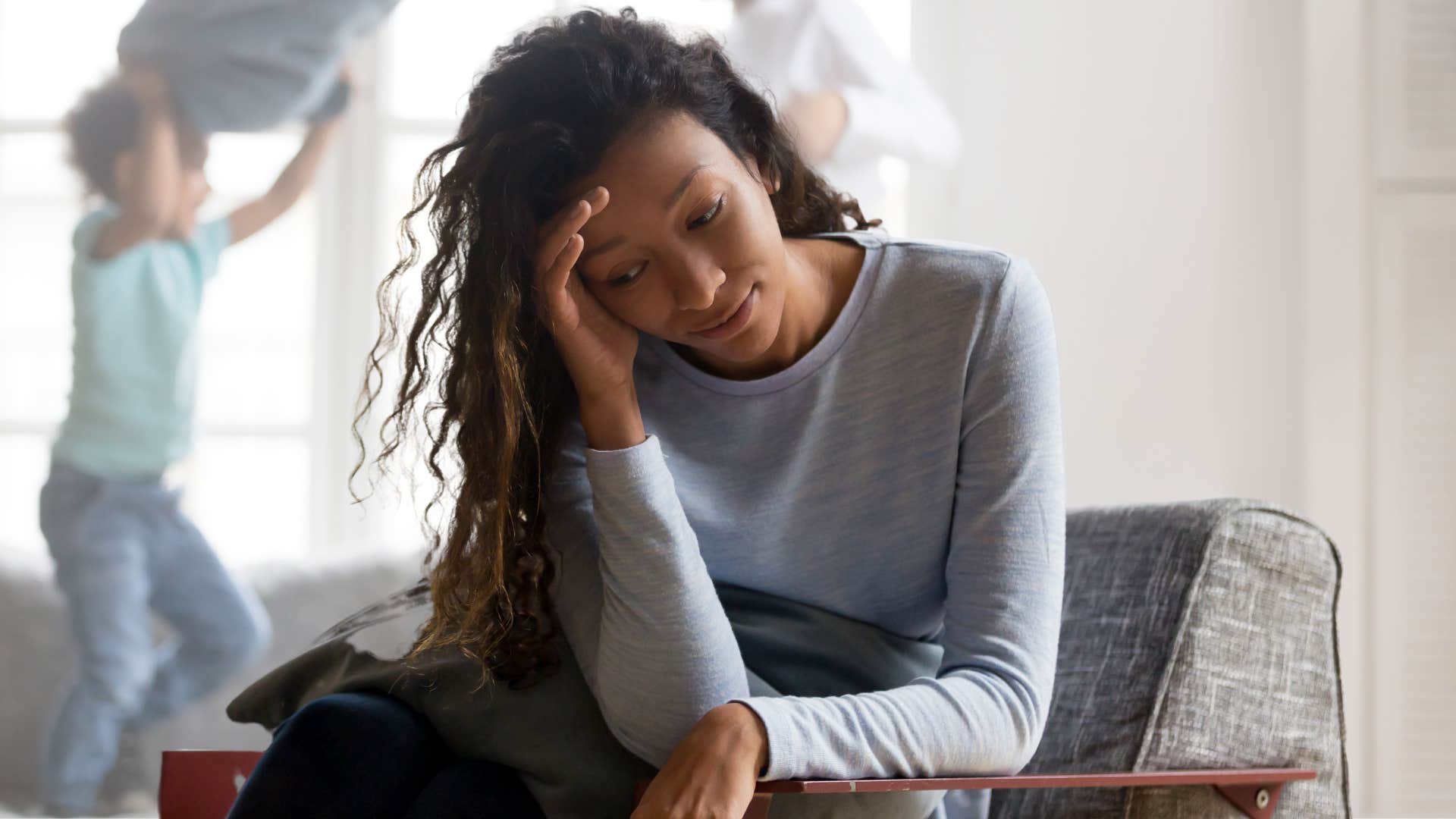 Woman looking stressed sitting on her couch.