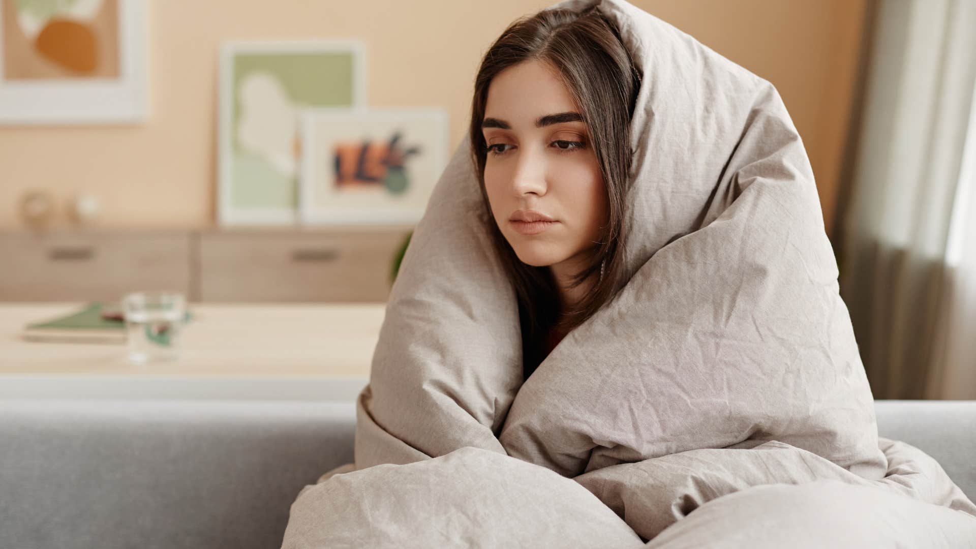 Woman looking tired under her blanket.