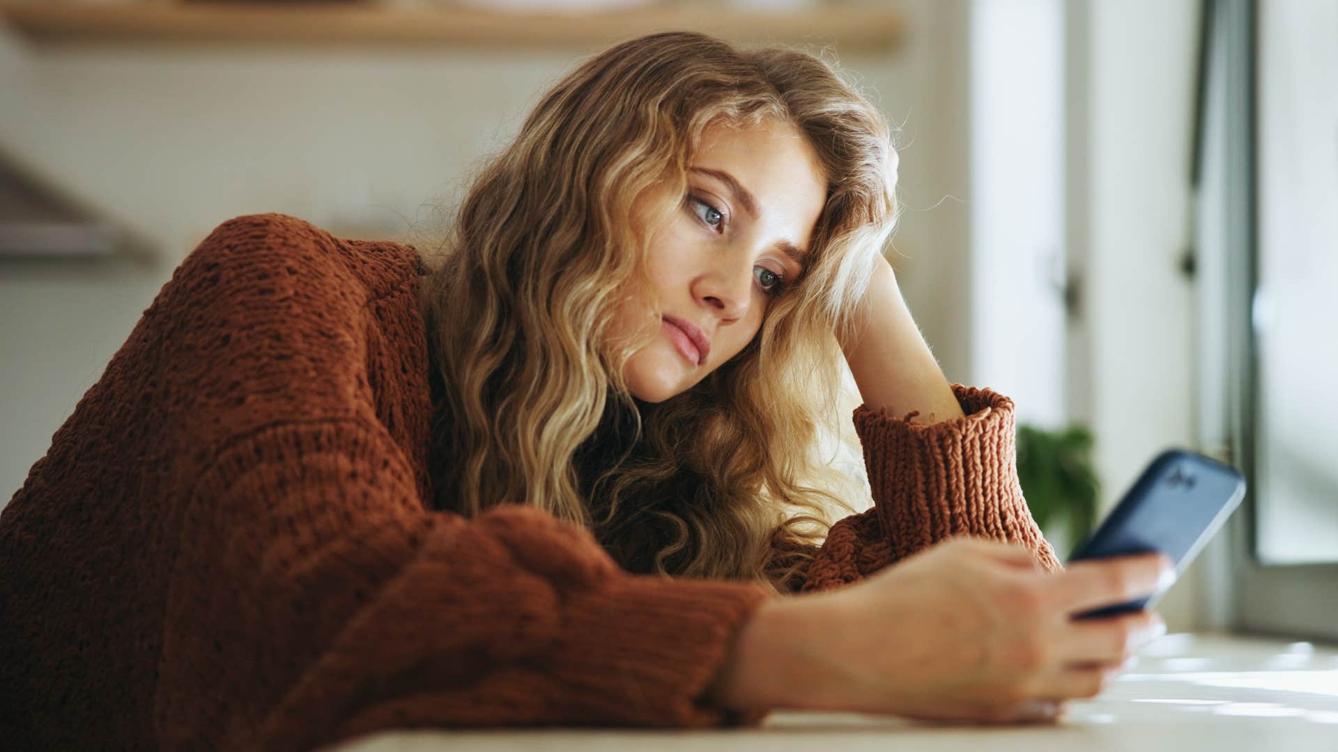 Sad woman typing on her cell phone.