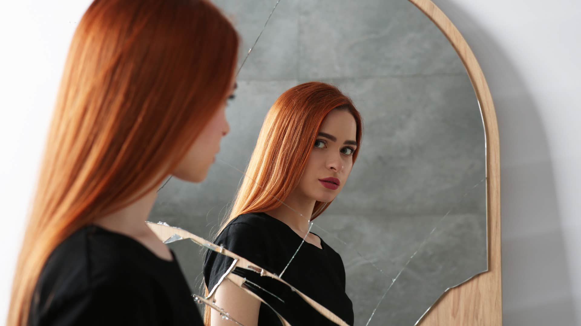 Woman looking sad staring in a mirror.