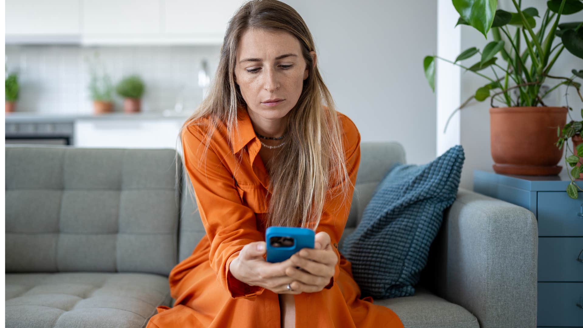 Woman looking sad down at her cell phone.