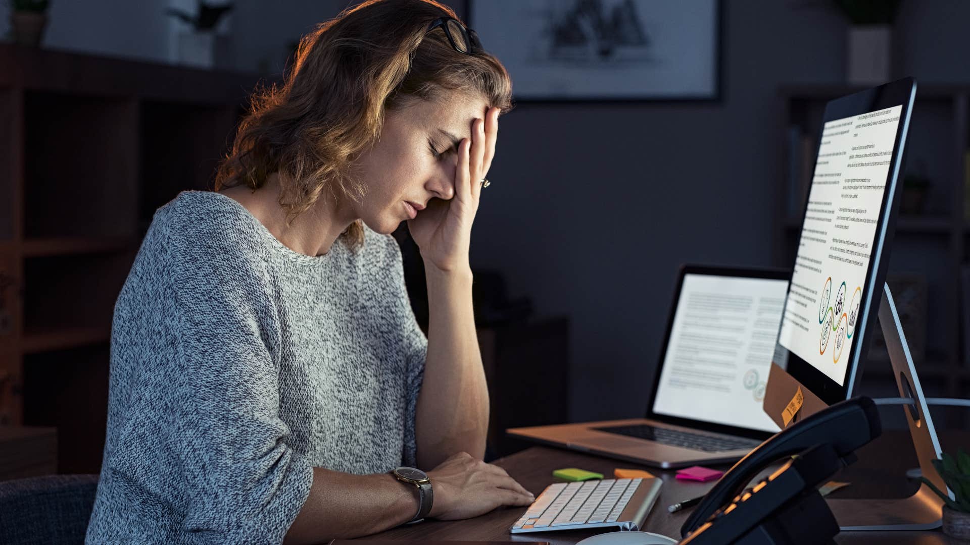 Tired woman working at her desk at night.