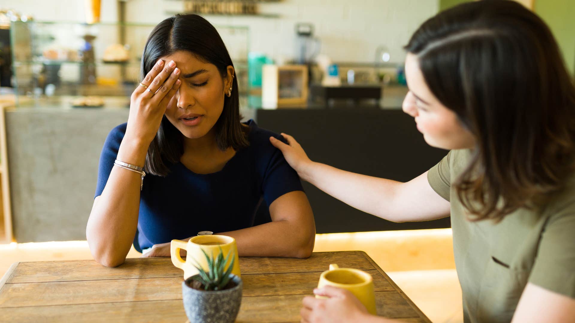 Female friend comforting another crying woman.