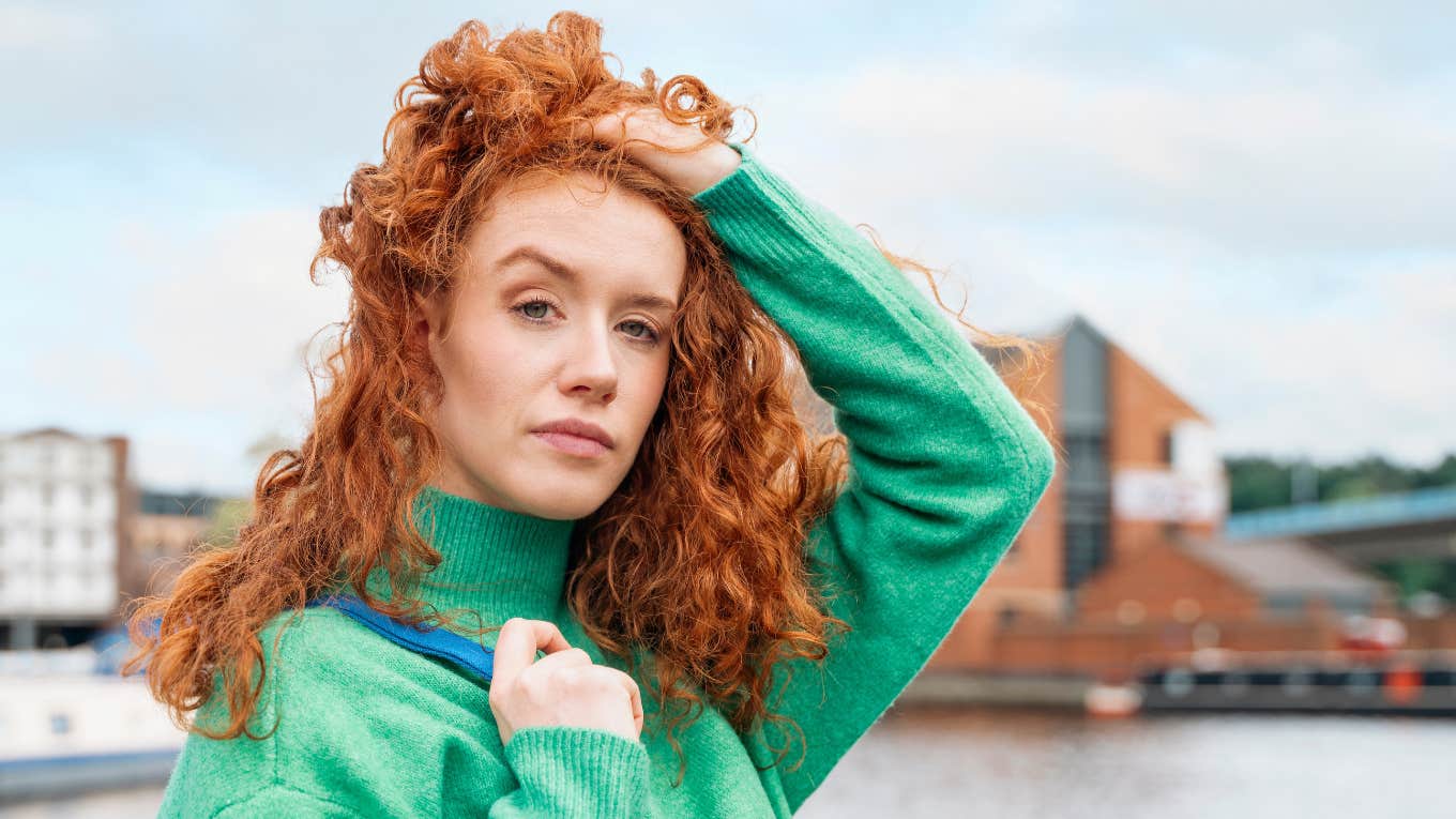 redheaded woman with curly hair posing outside