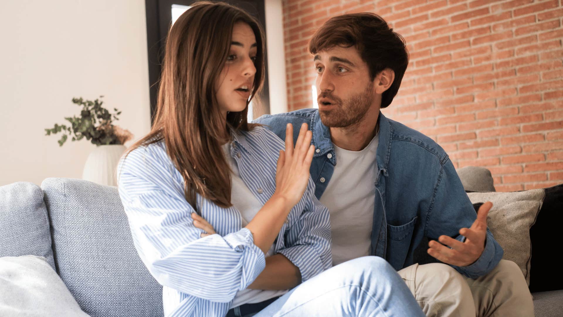 woman holding up hand to man while he argues back