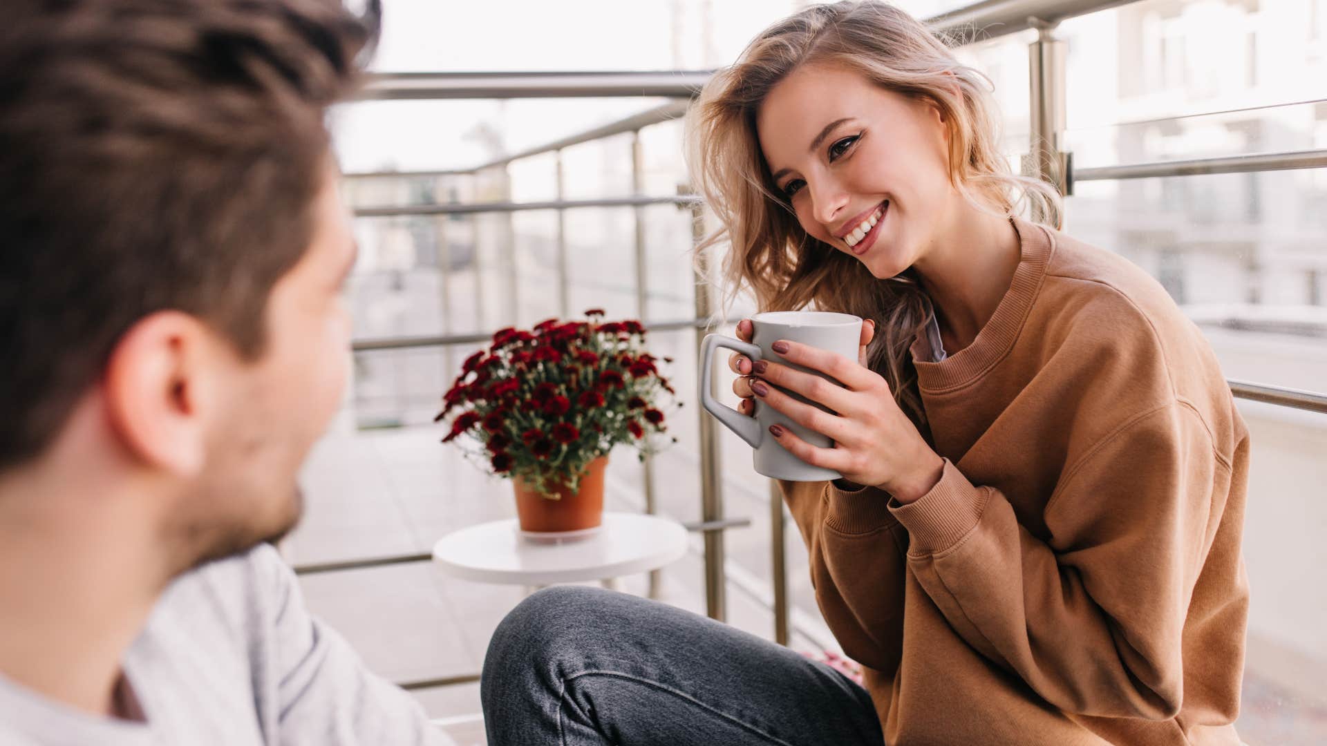 Woman smiling at a man and drinking coffee.