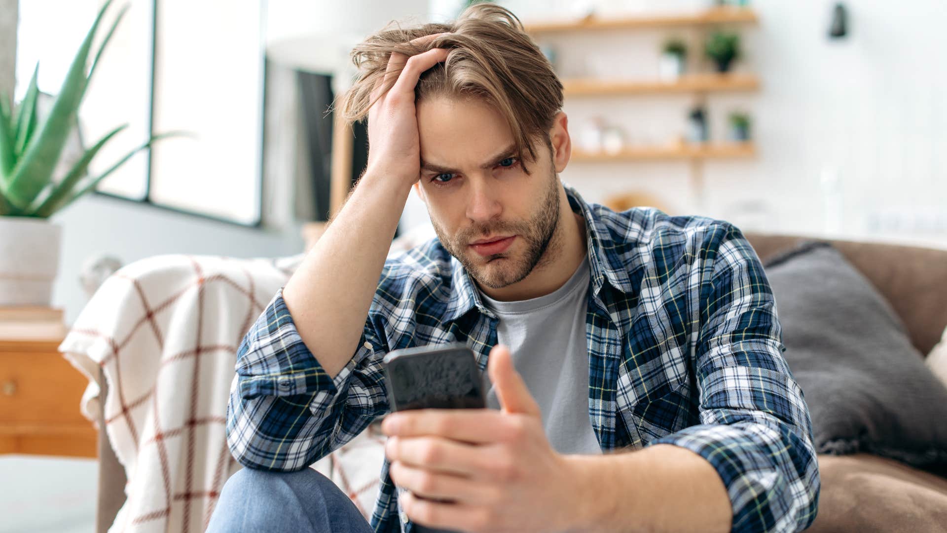 Adult man looking annoyed staring at his cell phone.