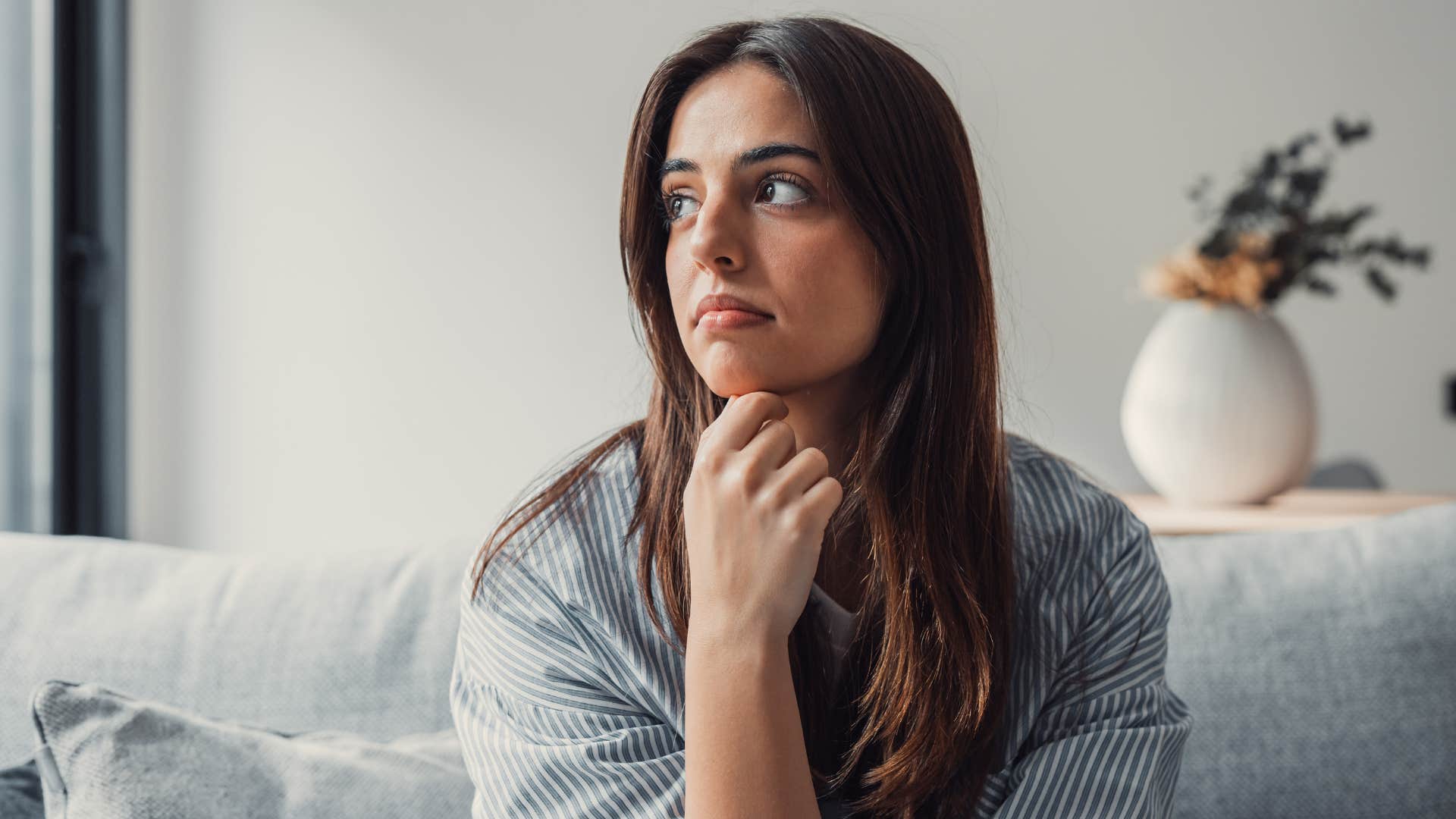 Sad woman holding her chin and looking away from the camera.