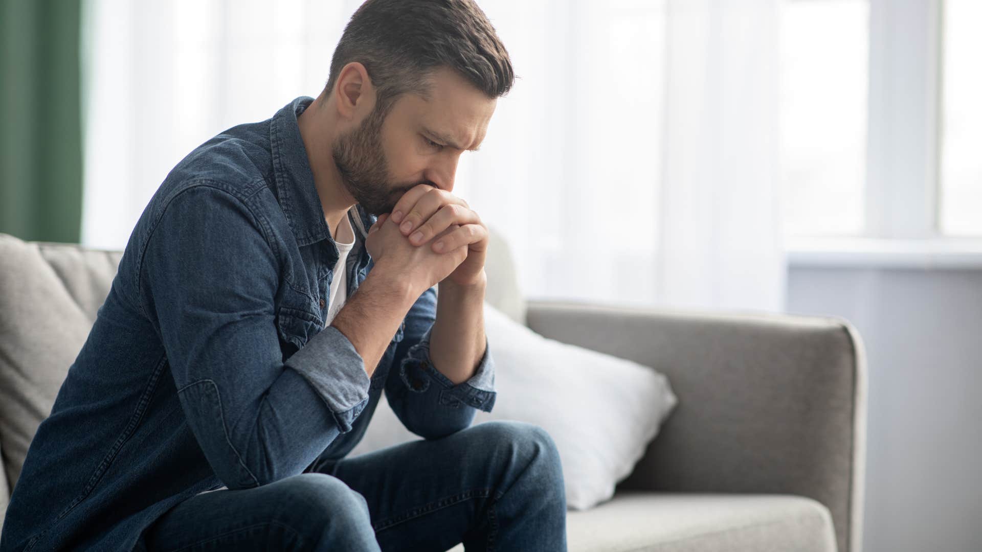 Man looking guilty sitting on his couch.