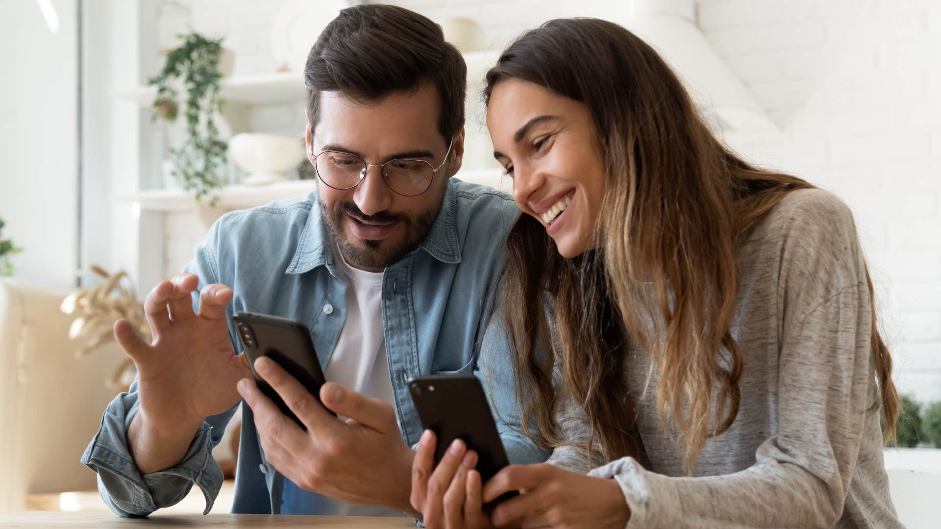 Man and woman smiling on their phones together.