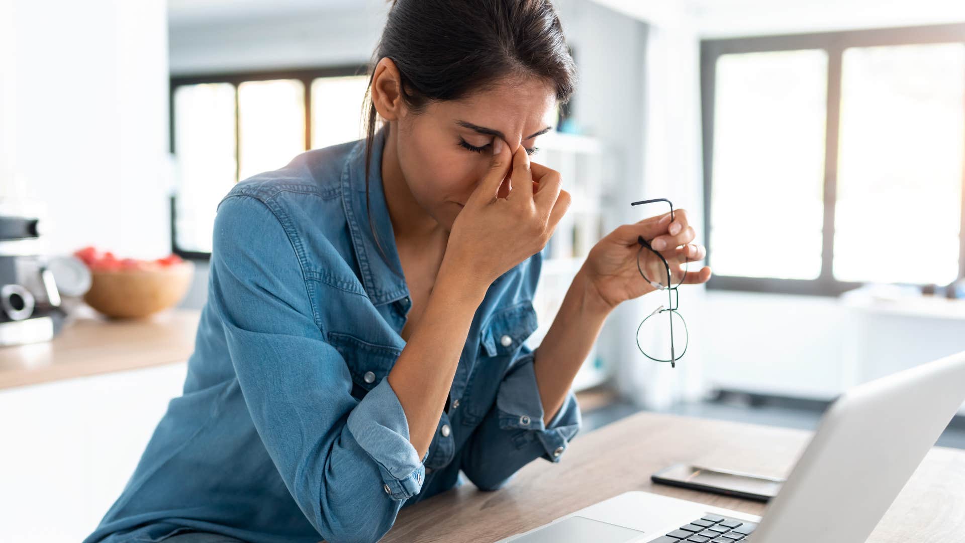 Woman holding her head and looking stressed at work.