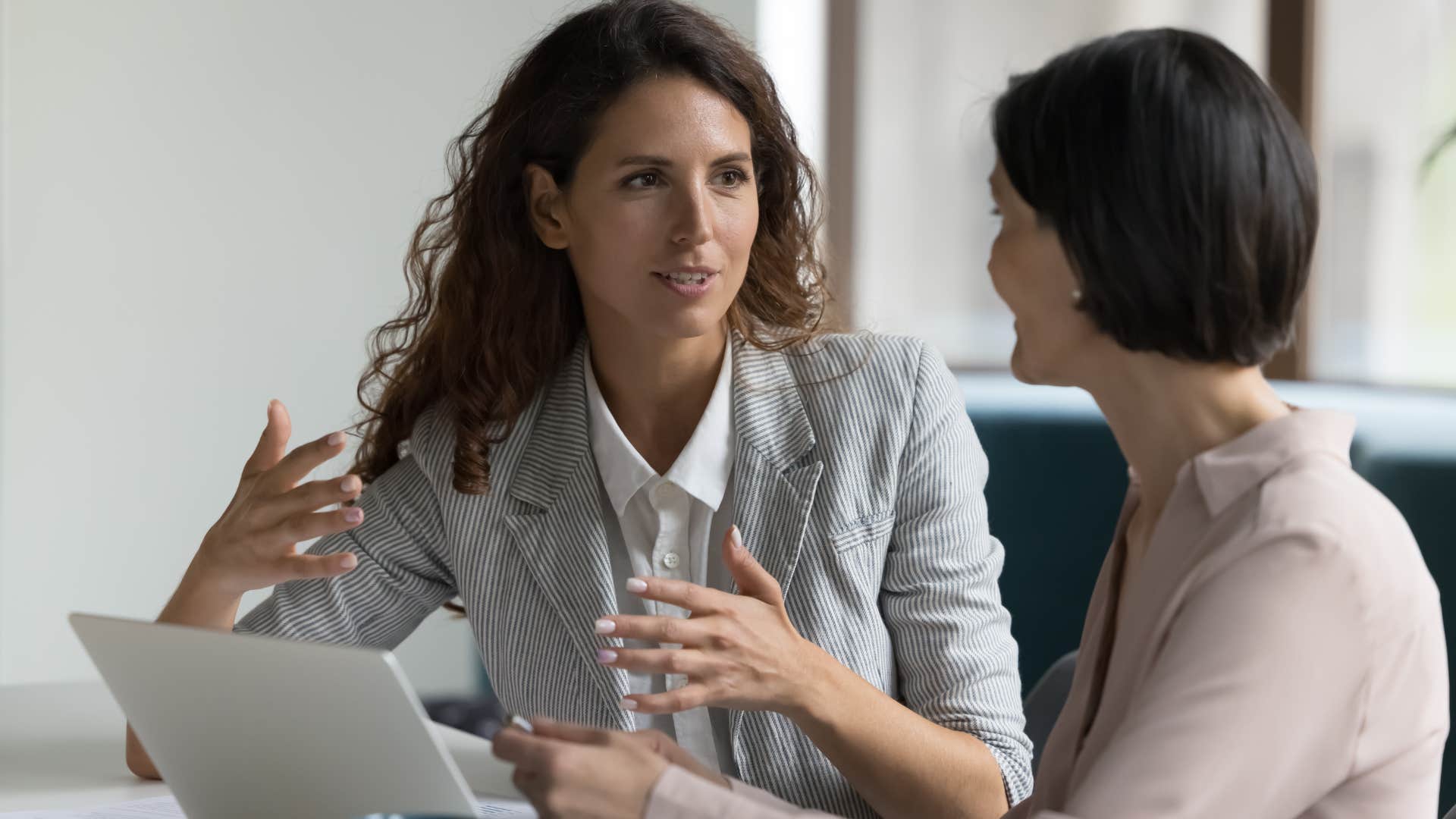 Female boss talking to an employee at her desk.