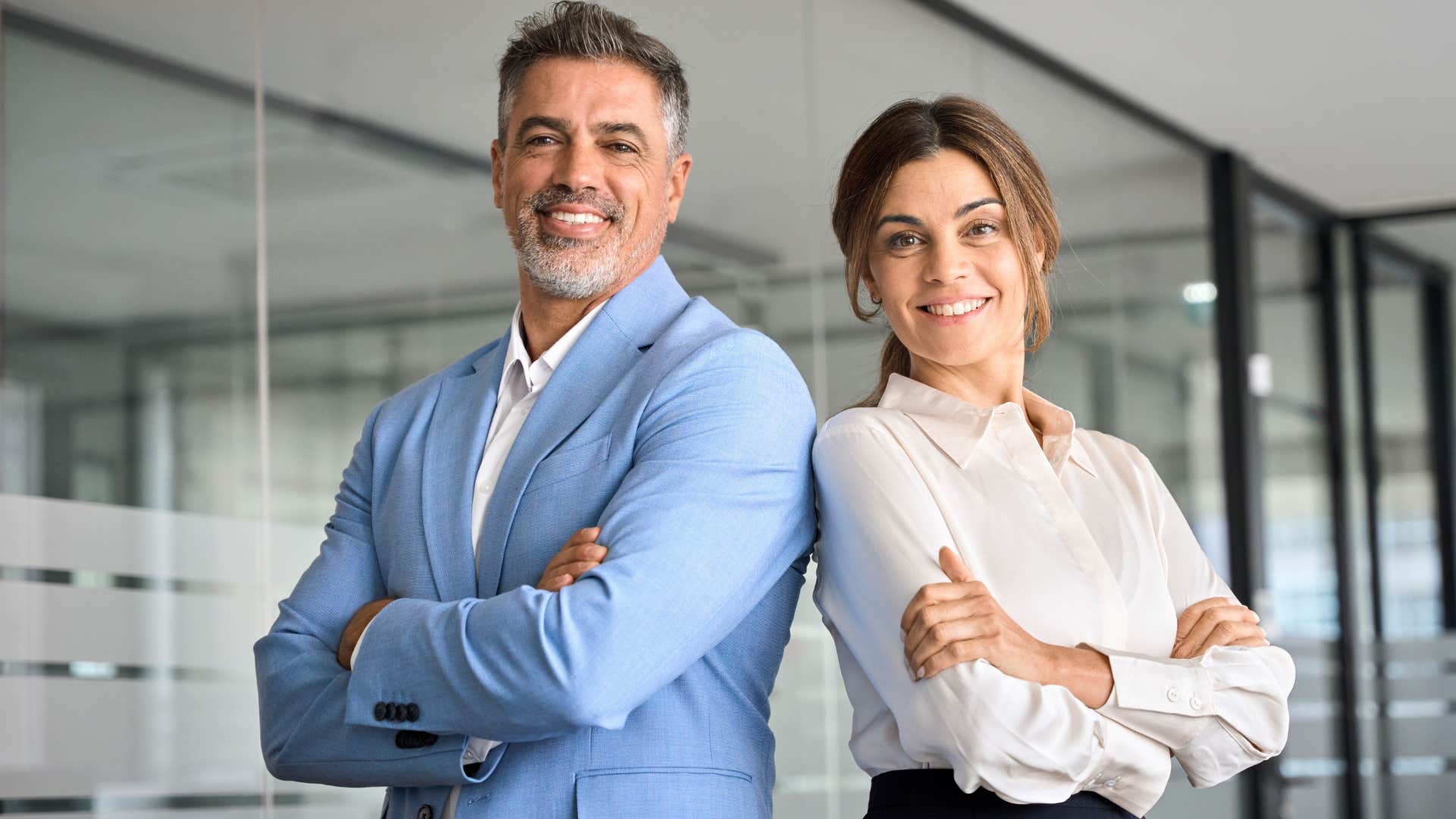 Man and woman standing back to back in a work office.