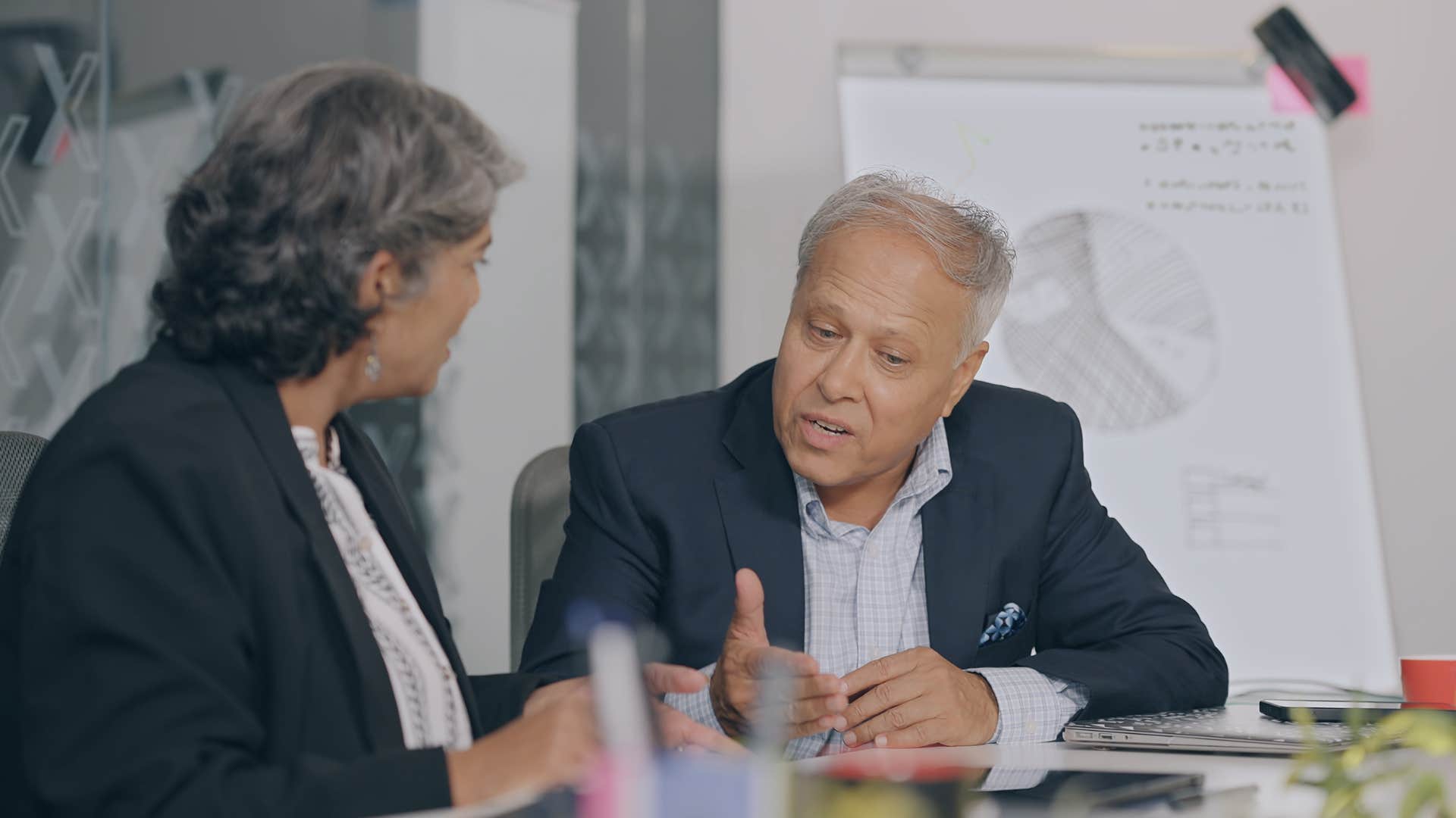 Older man talking to an older woman at work.