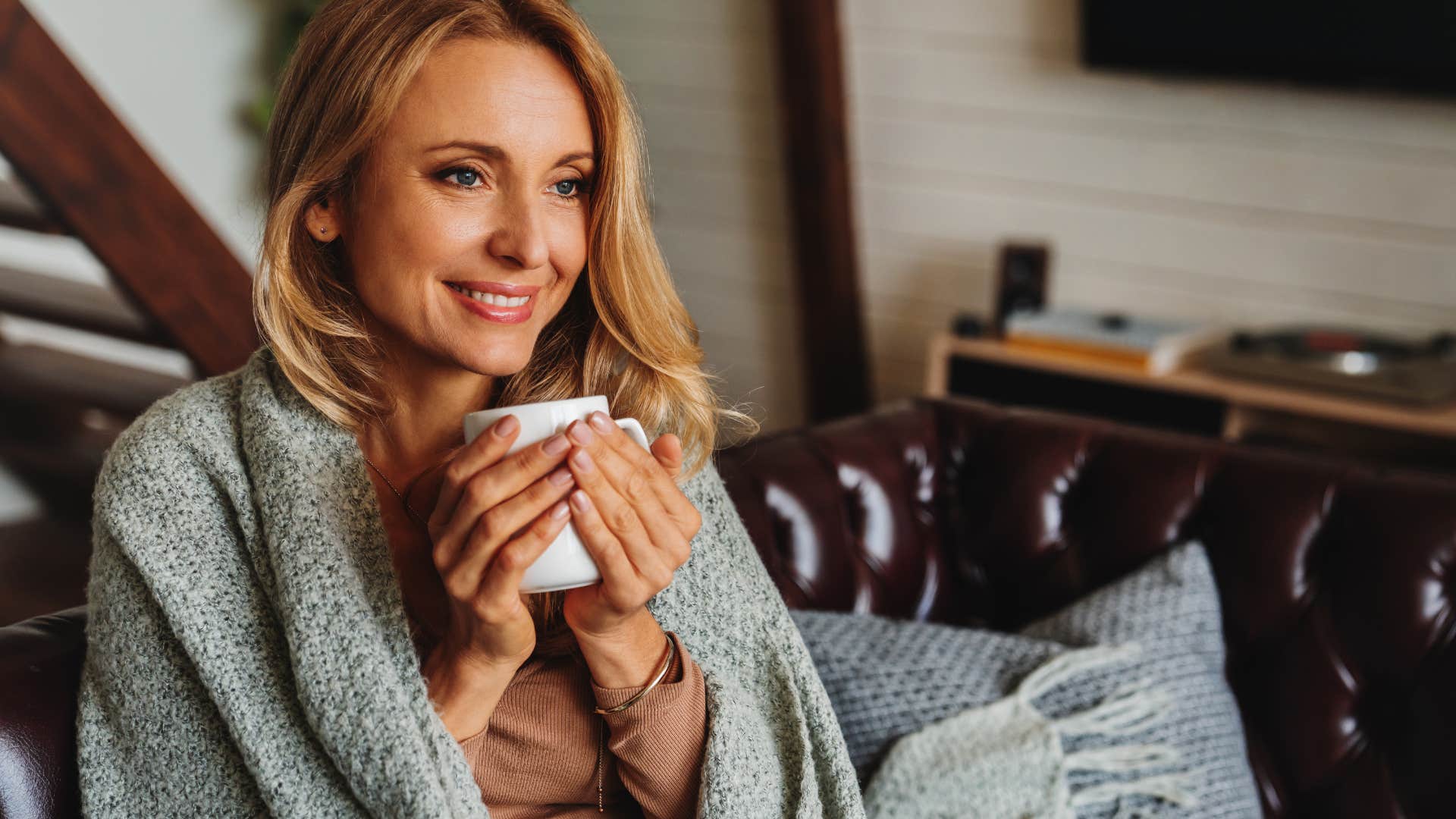 Woman smiling while holding her hot coffee.