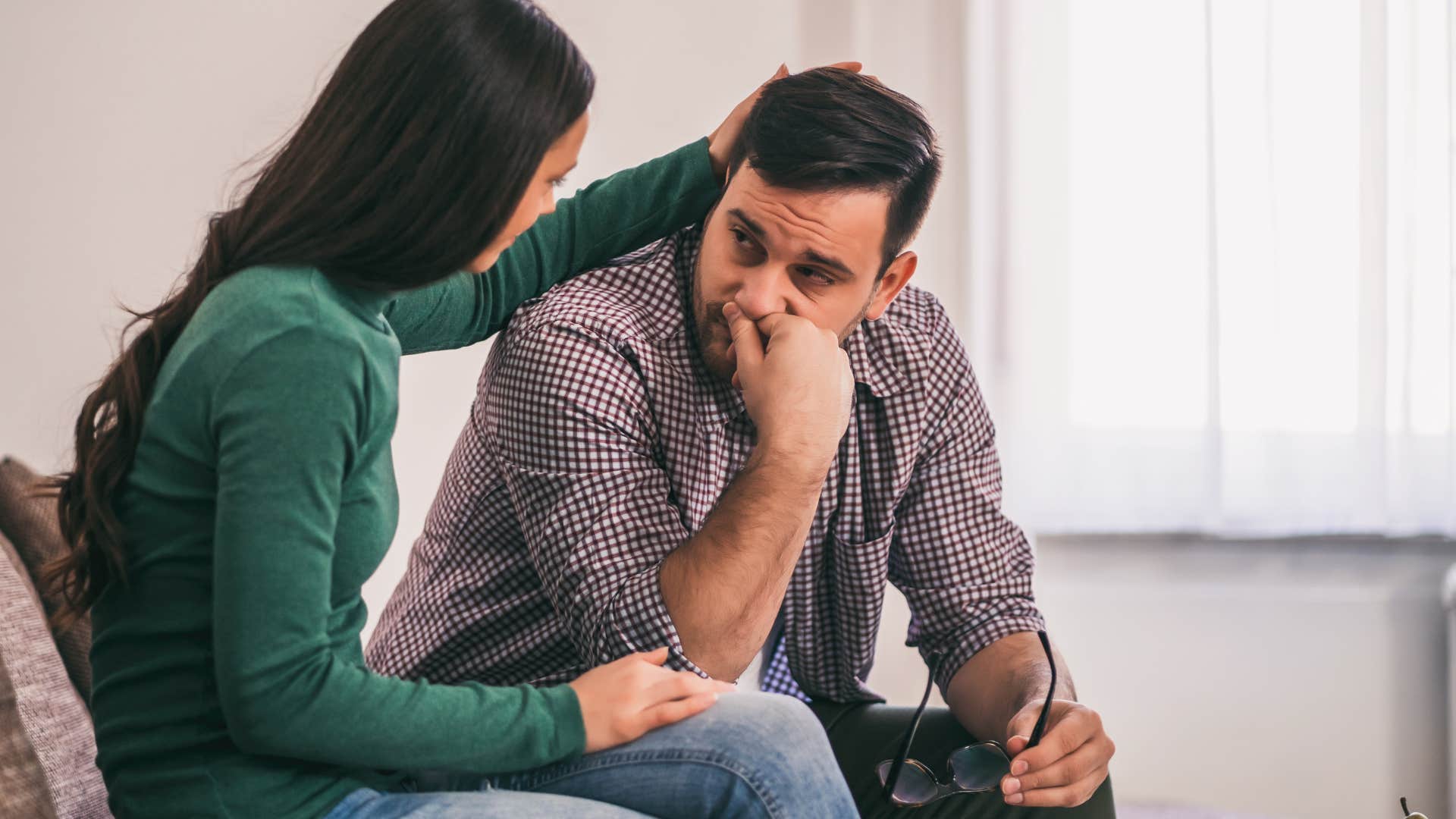 Man looking upset being comforted by his wife.