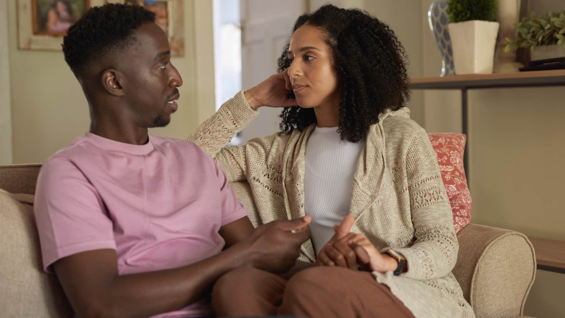 Couple sitting on the couch having a serious conversation.