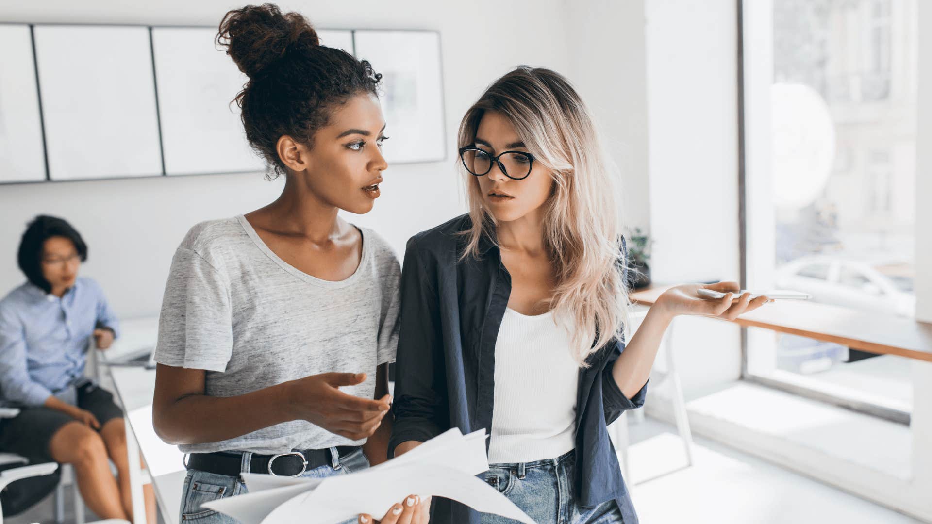 two women disagreeing while discussing paper work