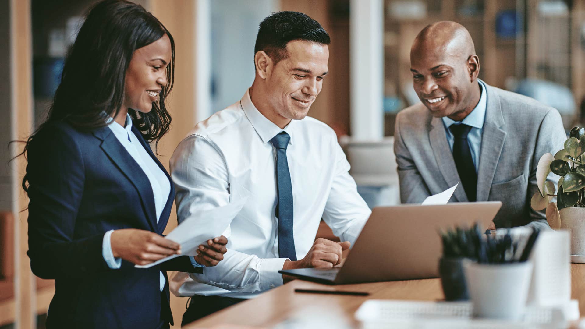 three coworkers discussing something while looking at laptop