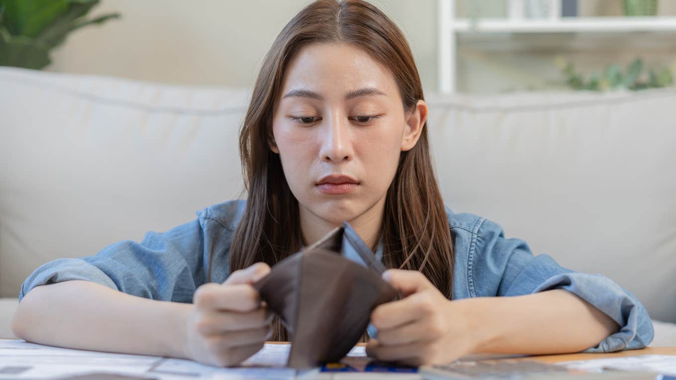 woman looking into empty wallet