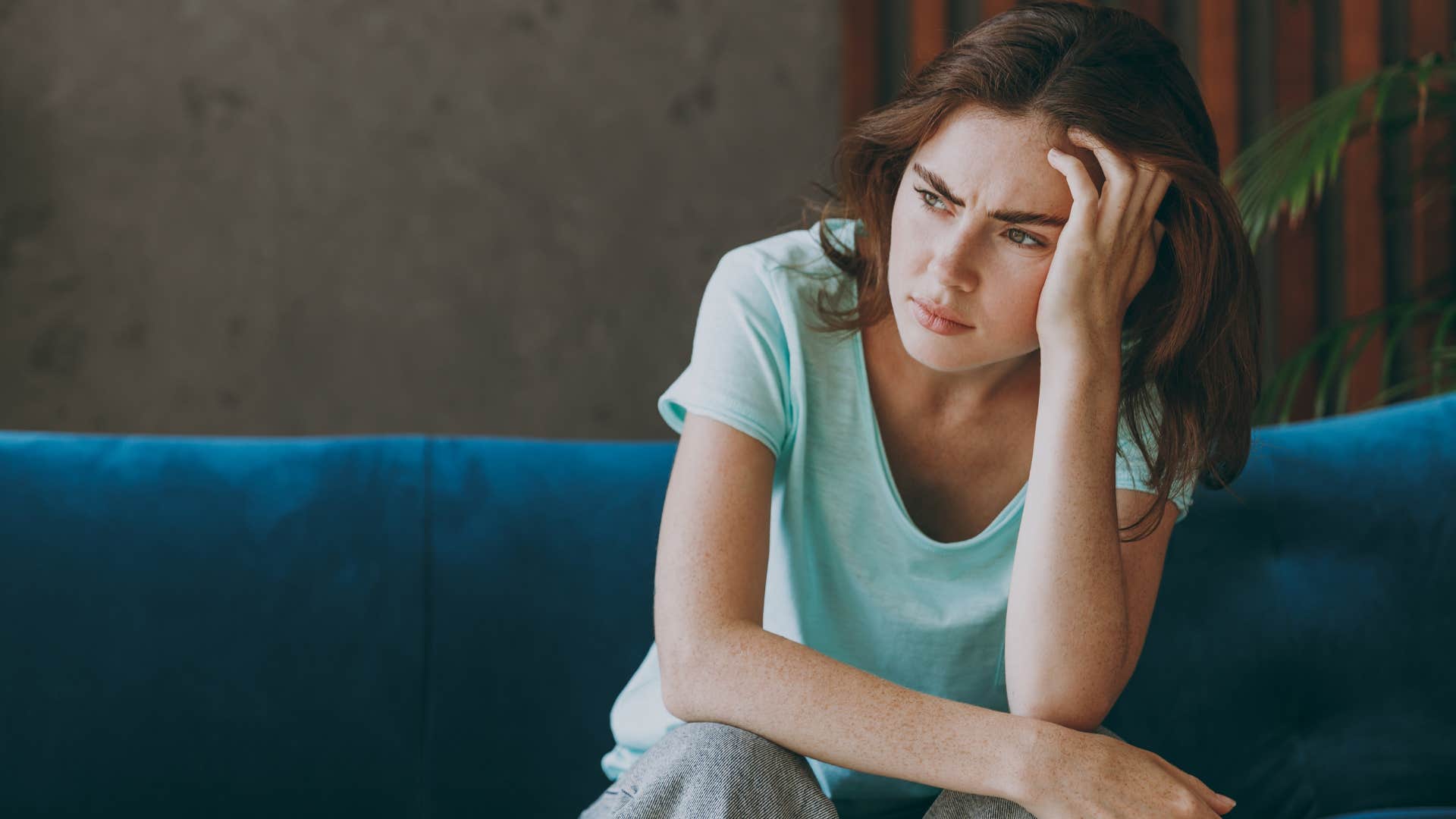 Woman overthinking on her couch.