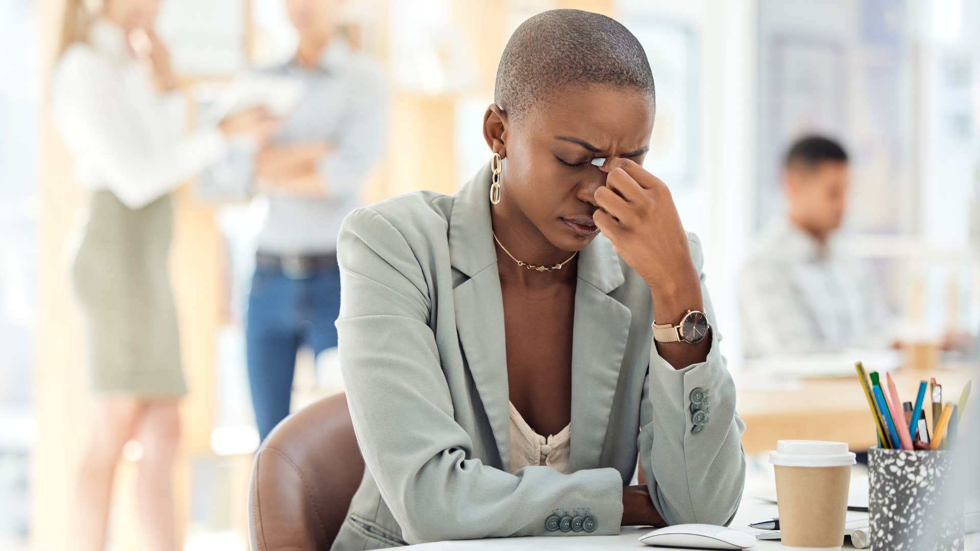 Woman holding her head in her hands at work.