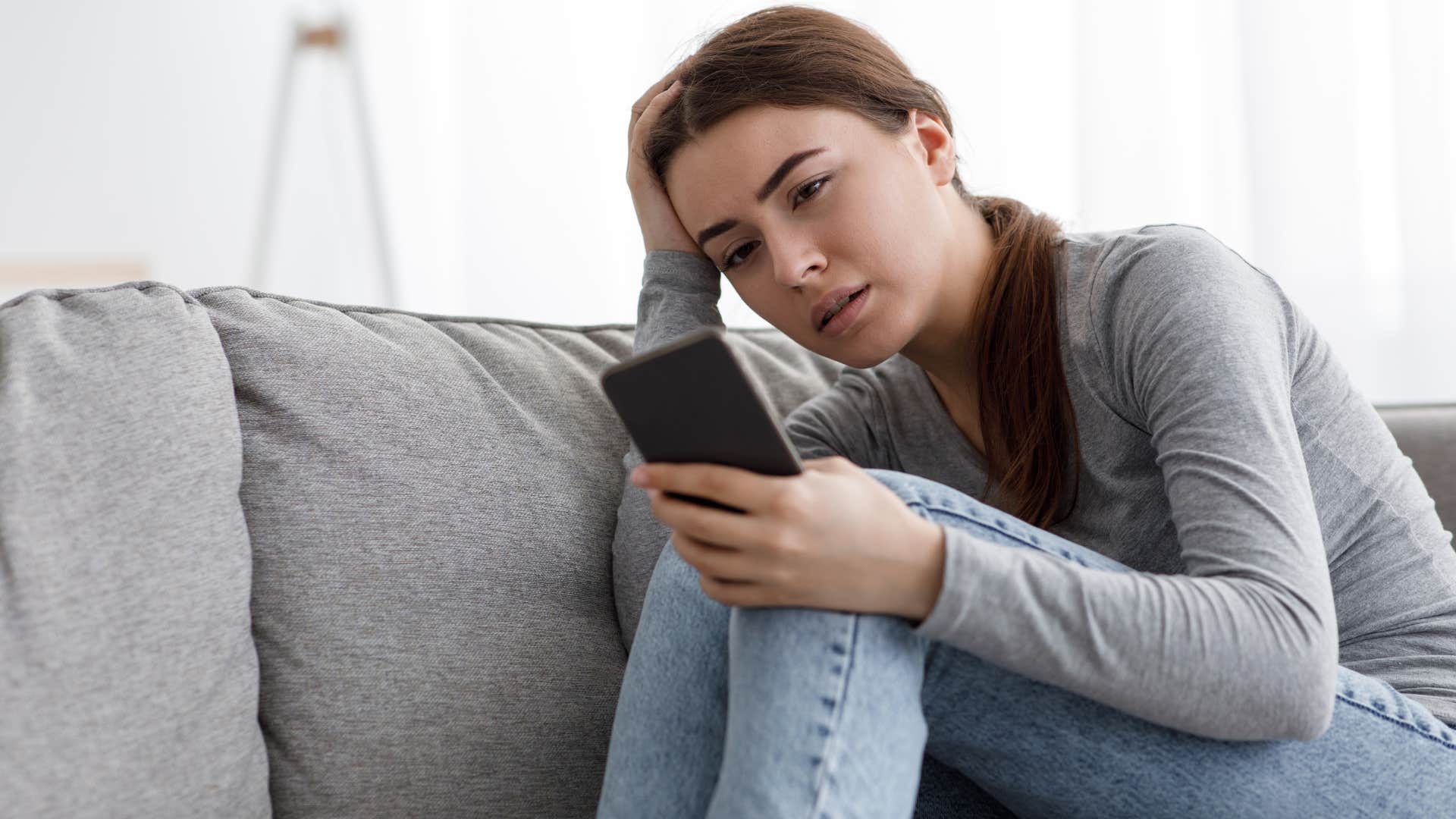 Woman looking annoyed staring at her cell phone.