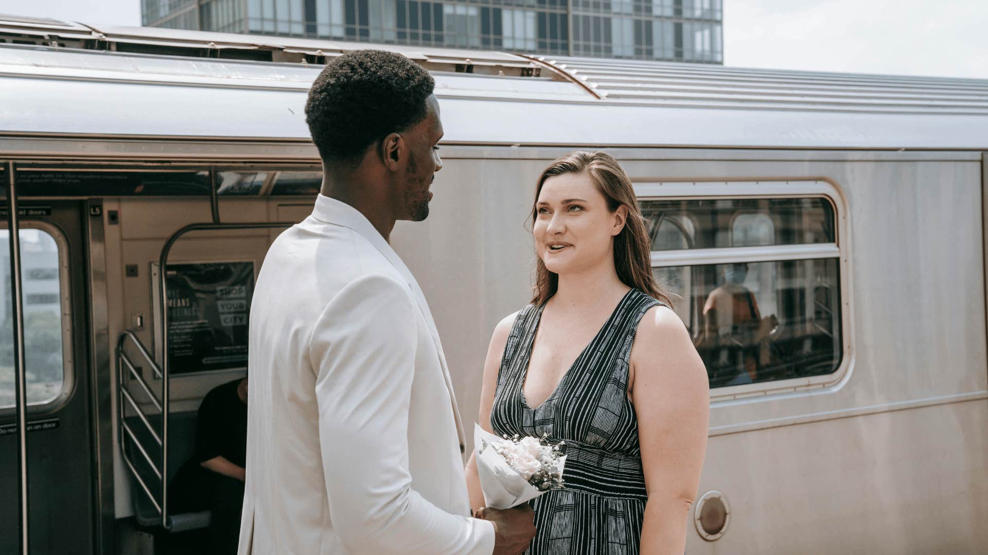 man and woman talking next to train