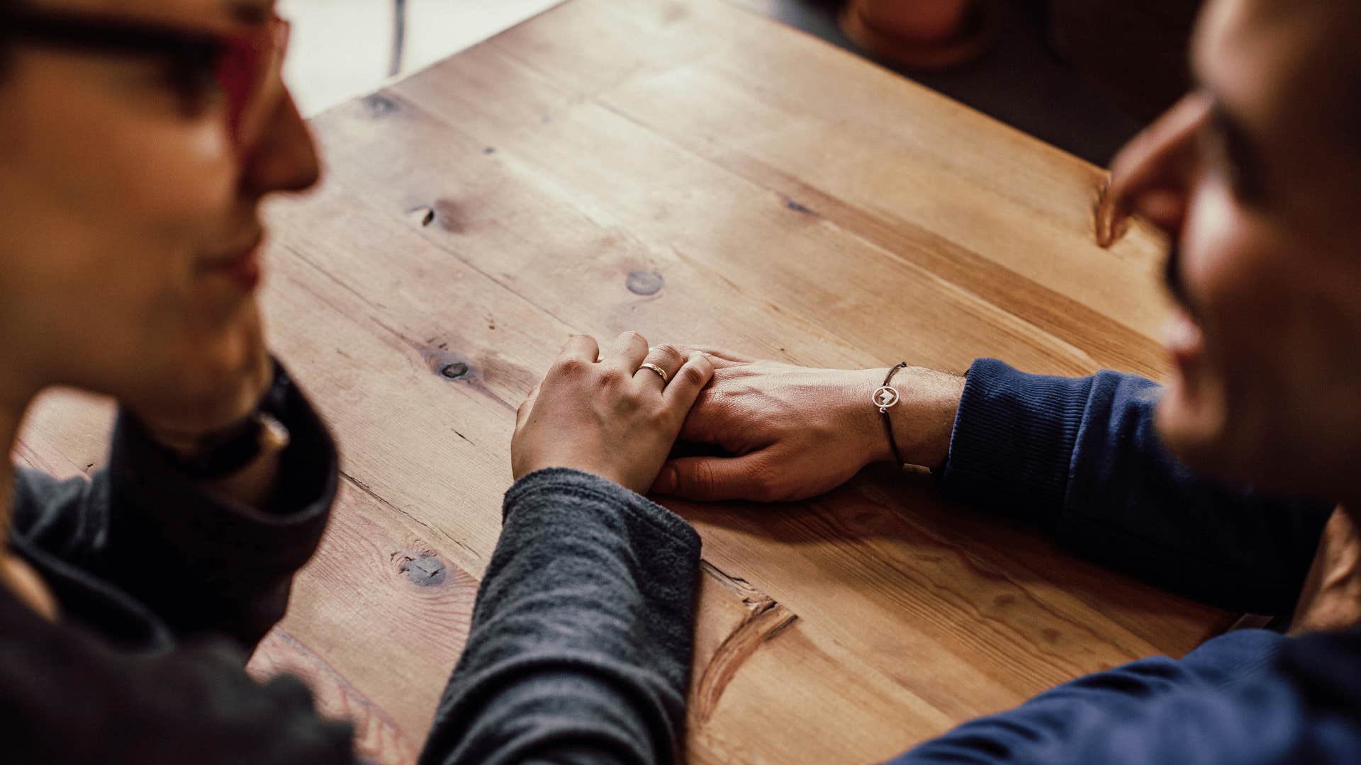 couple holding hands on table