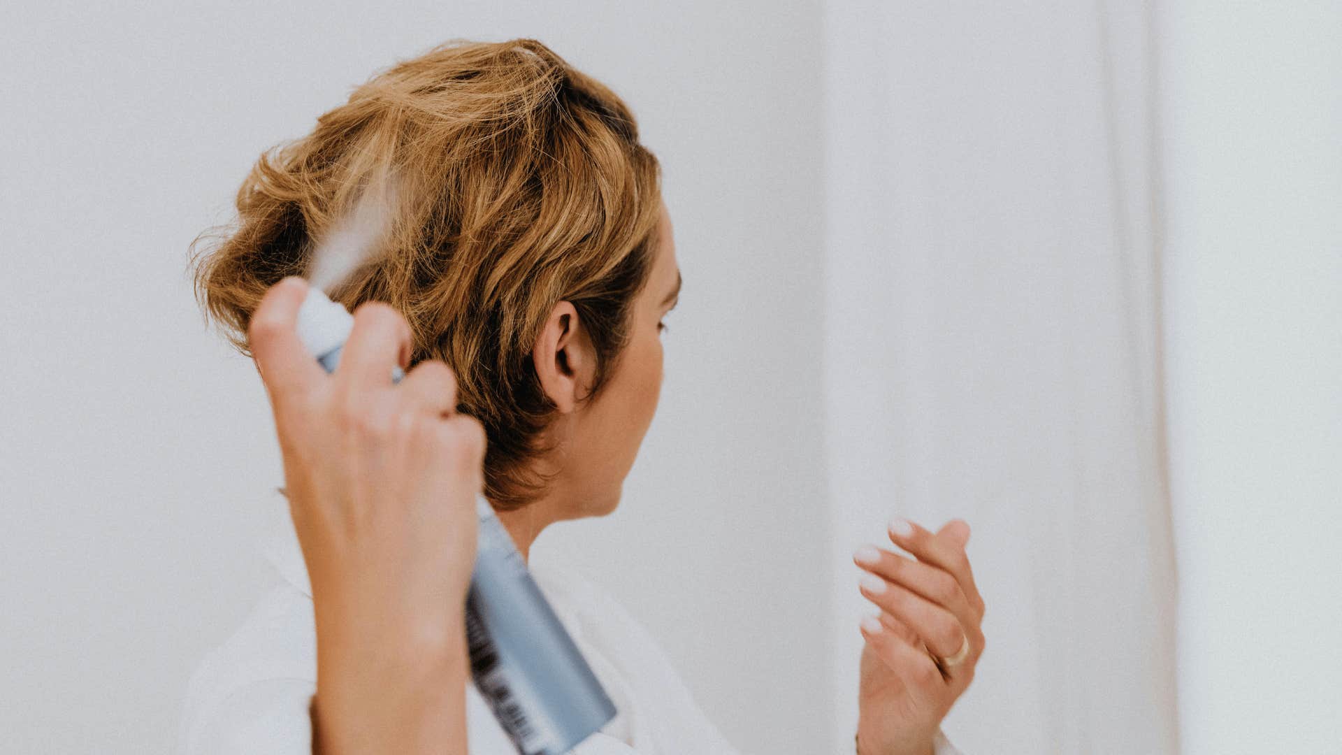 woman putting hair spray in hair