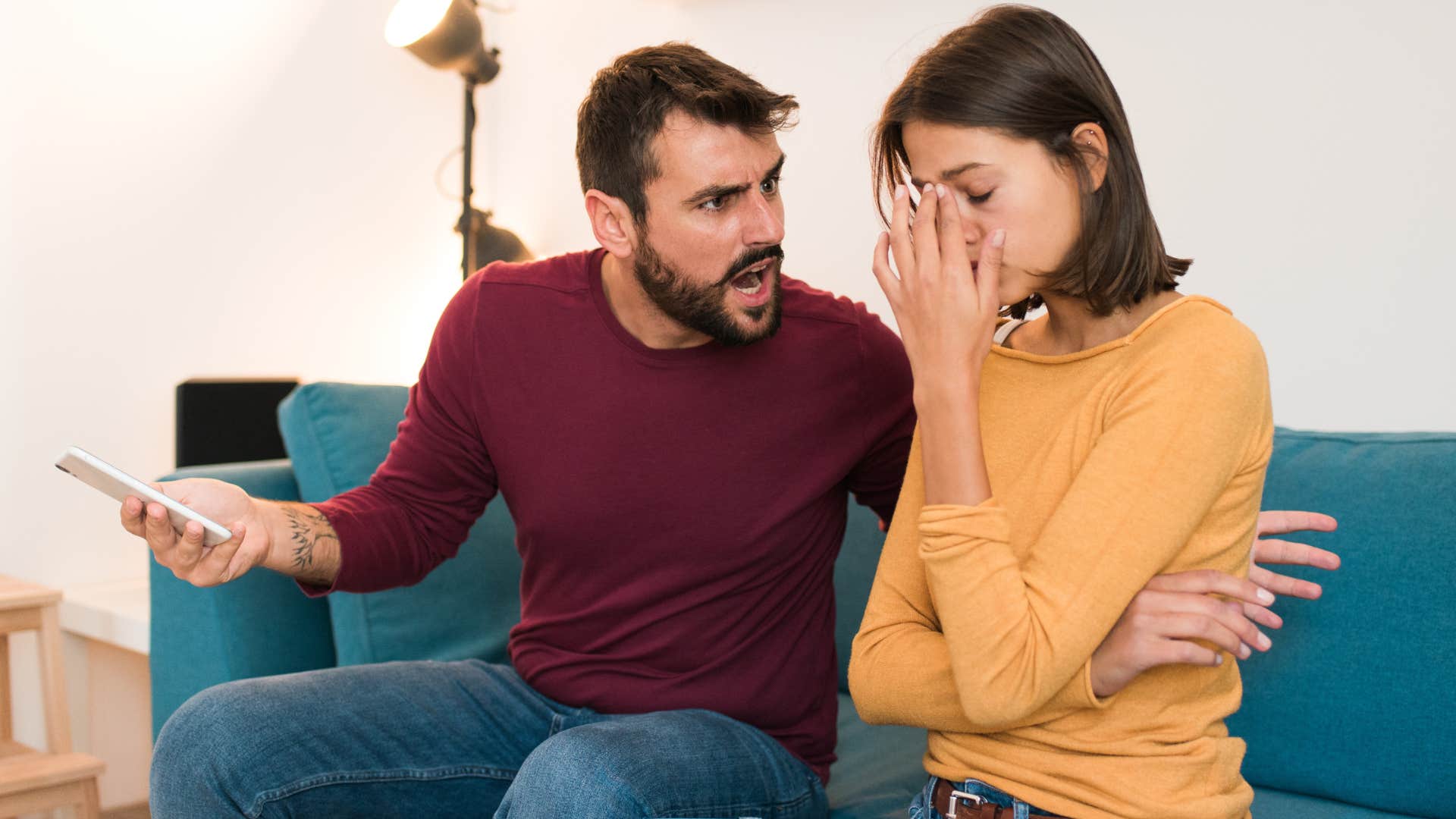 Man yelling at a woman with her face in her hands.