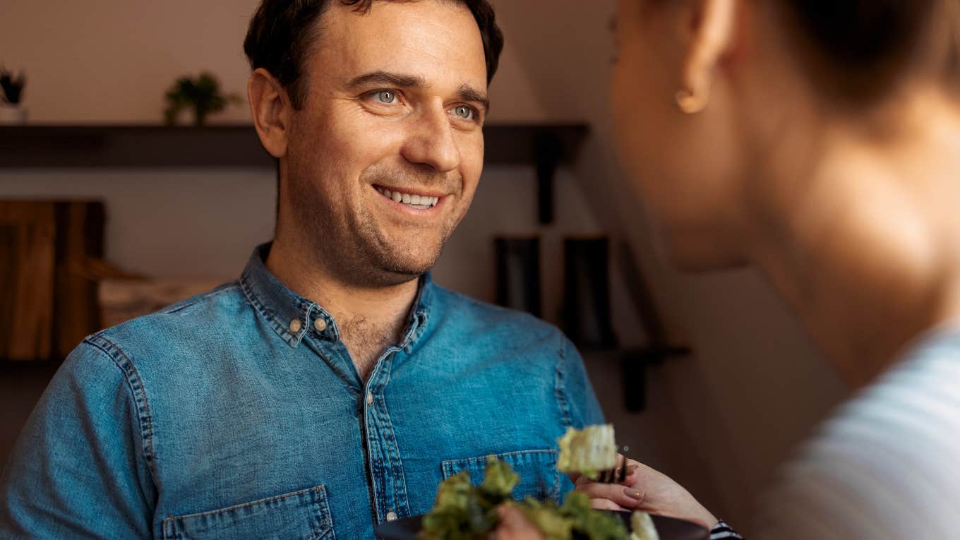 Man lovingly handing woman a plate of food.