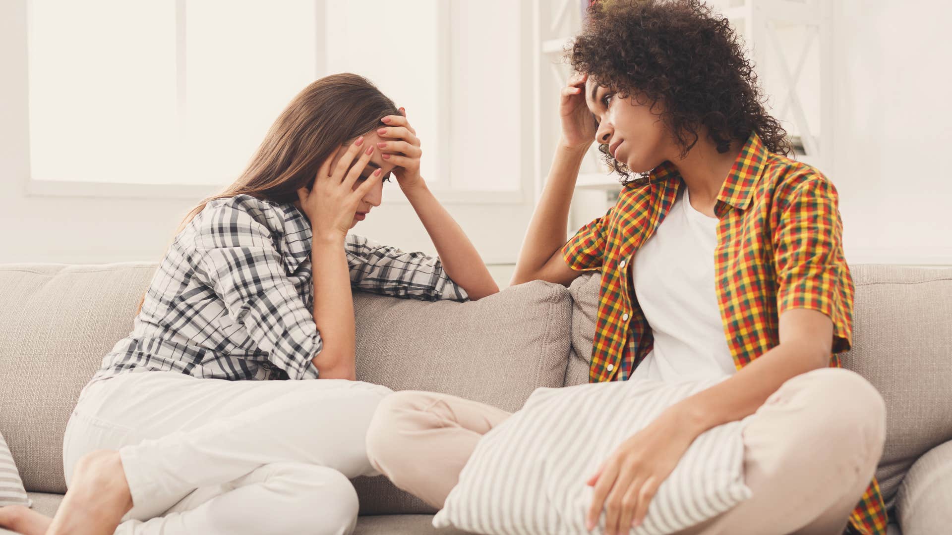 Couple looking upset sitting together on the couch.