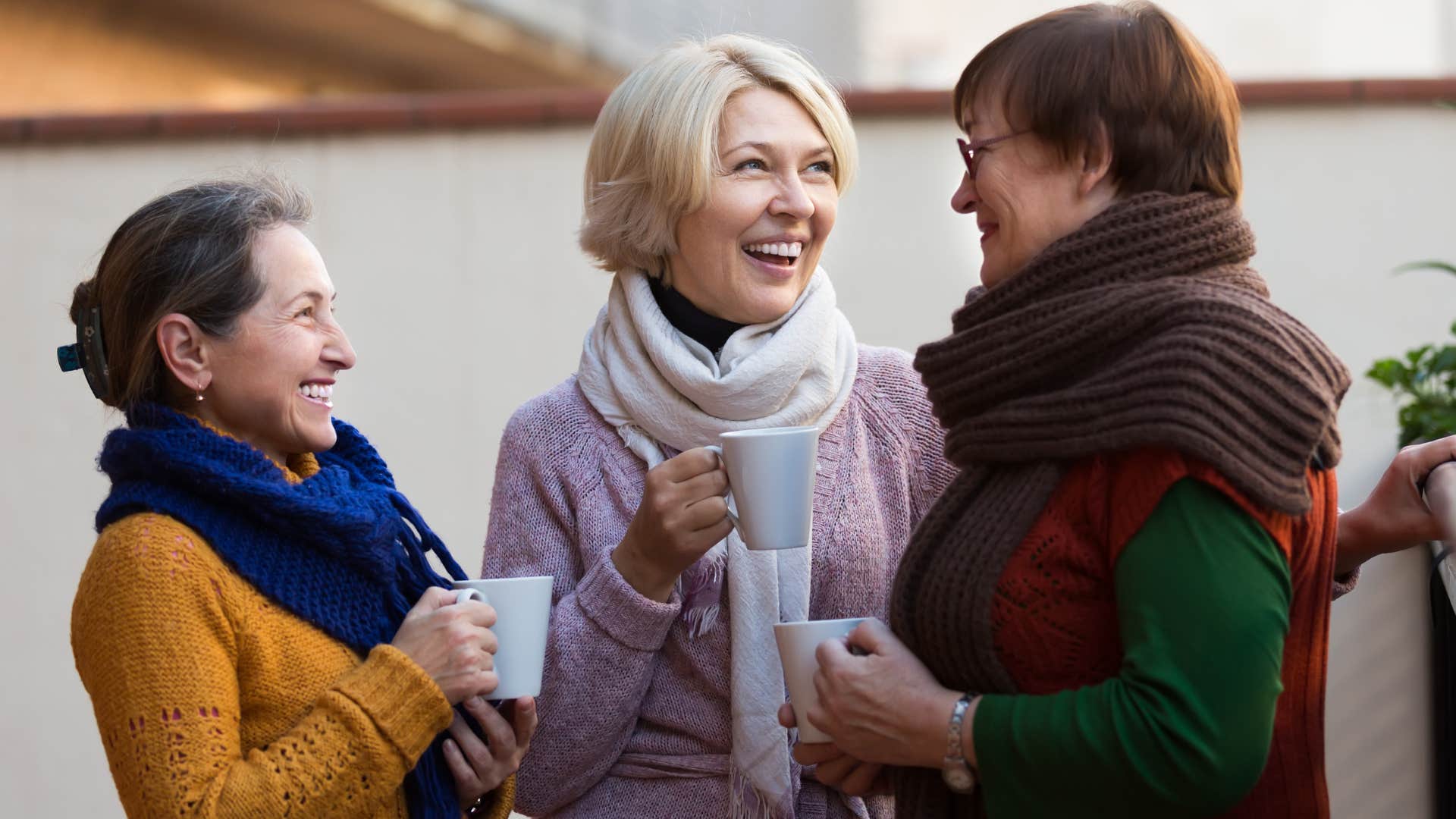 Three older women smiling and talking.