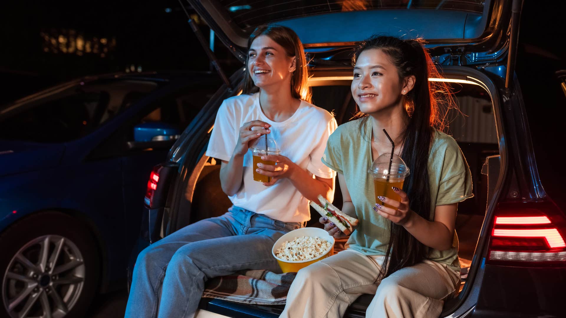 Two friend sitting in their car at a drive-in movie theater