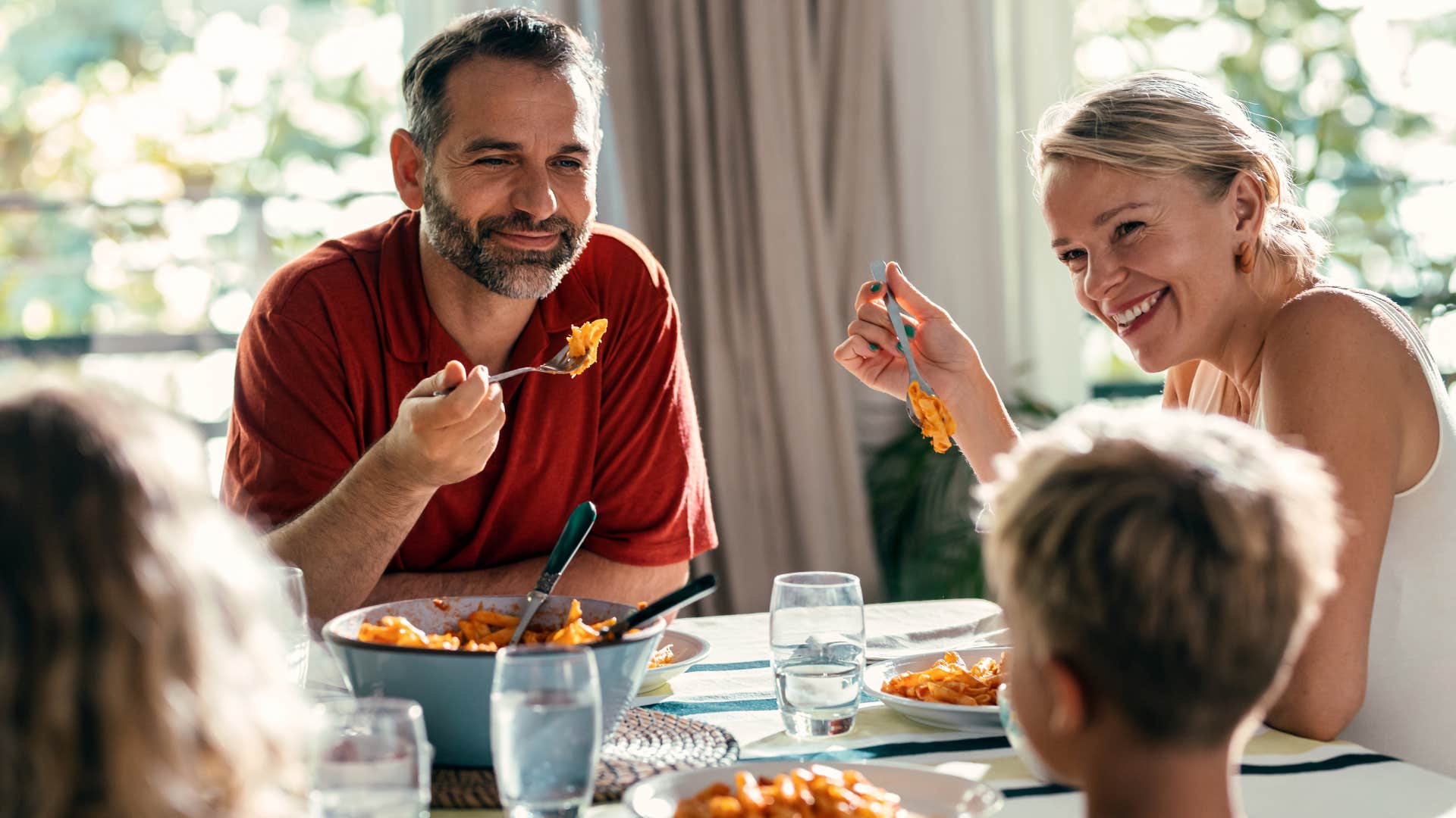 Family smiling while eating dinner together