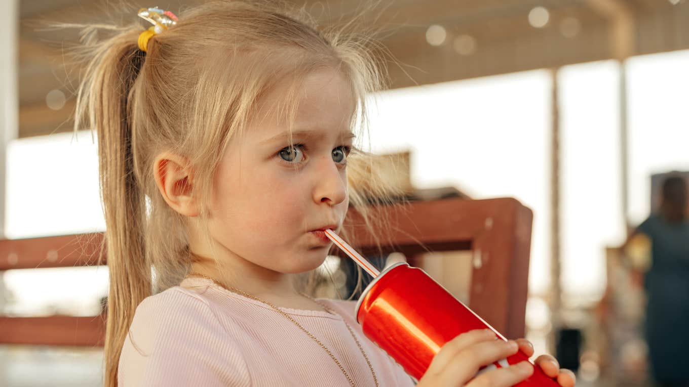 Little girl drinking out of a straw on school playground